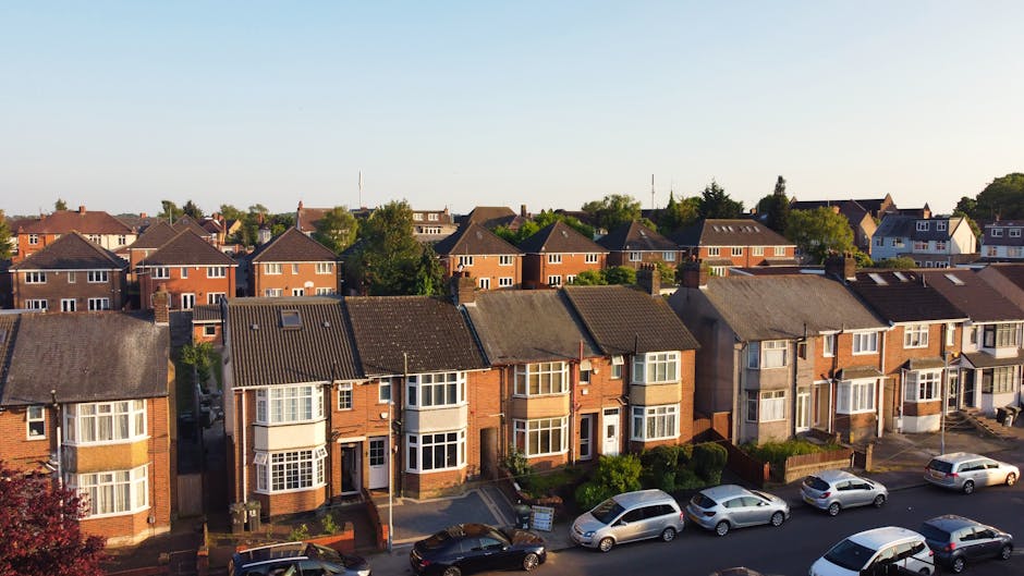 A row of multi-storey terraced houses painted in pastel colors including cream, light purple, yellow, blue, and turquoise, situated on a street in Barnes. The houses have bay windows, some with white